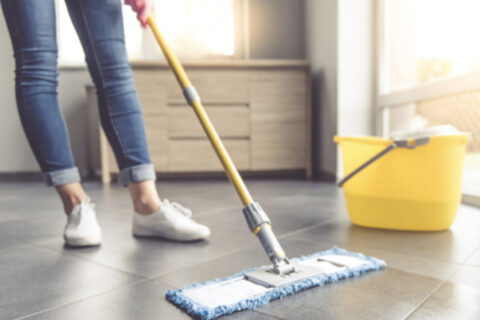 Person cleaning floor with mop and bucket in bright room