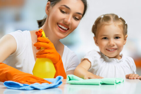 Mother and daughter cleaning with colorful cloths and spray